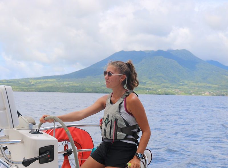 Student steering sail boat past St Kitts on Caribbean diving camp