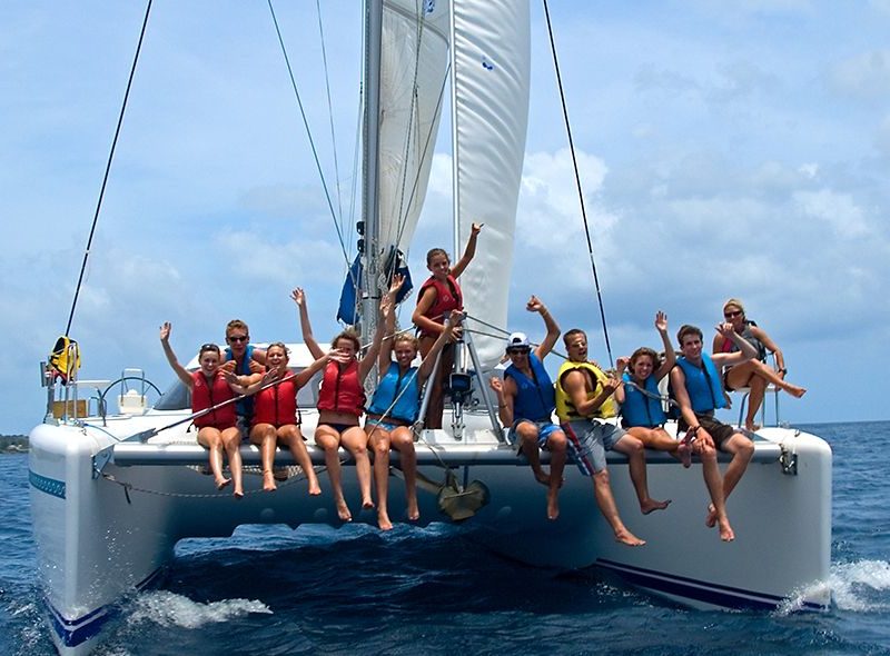 Teens sitting on bow on catamaran on summer sailing camp