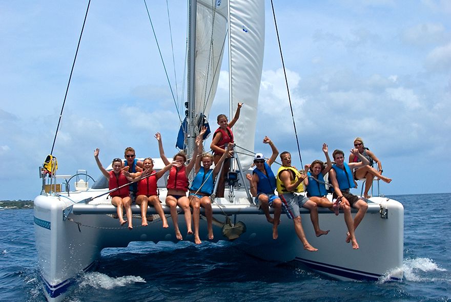 Teens sitting on bow on catamaran on summer sailing camp