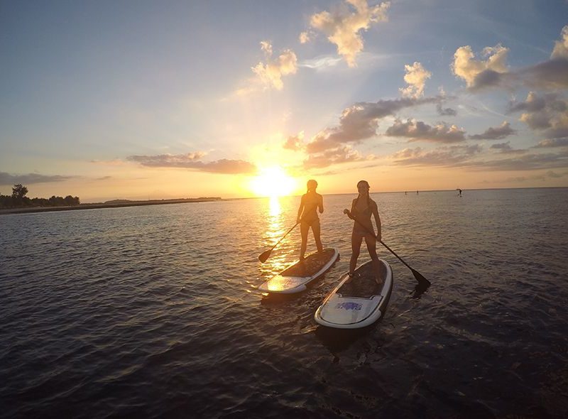 Teens paddle boarding at sunset on advanced scuba program