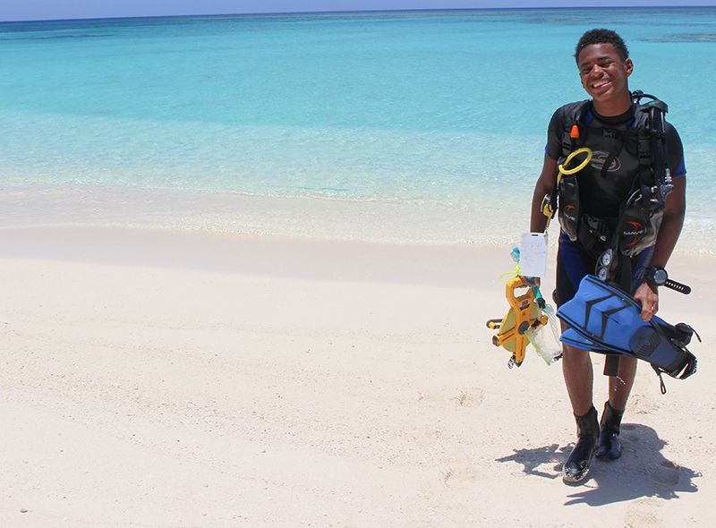 Teen in scuba gear on beach in Curacao for marine biology program