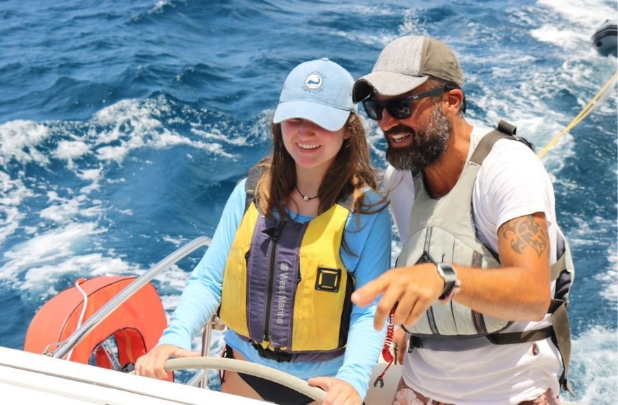 student at helm of boat with sailing instructor abroad in the Caribbean