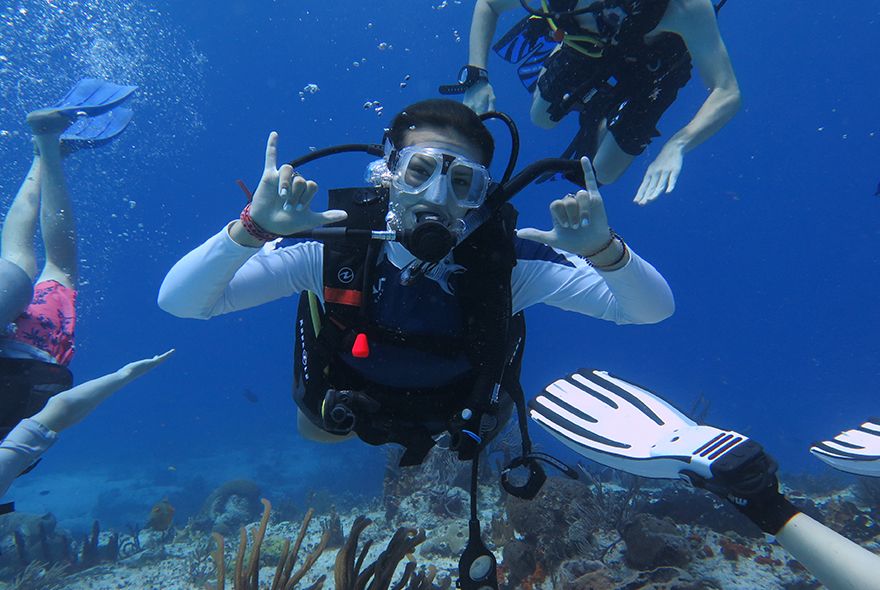 Teens scuba diving on coral reef on underwater summer teen trip