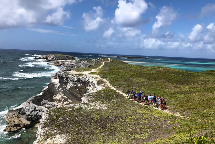 Group of high school students and marine science summer job hike near beach abroad