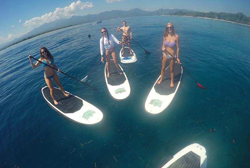 Teens paddle boarding in Caribbean on summer scuba diving camp