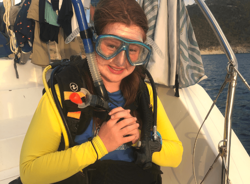 Middle school student in dive gear on catamaran at scuba program
