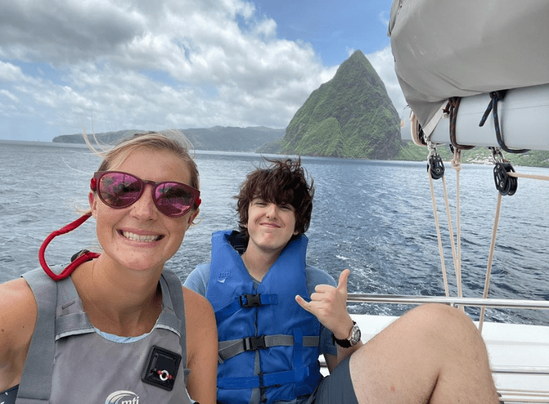 Middle school student and instructor on catamaran with Caribbean island in background