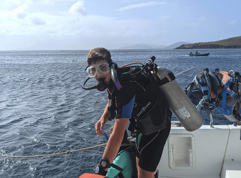 Teen in dive gear prepares to enter water at advanced scuba camp