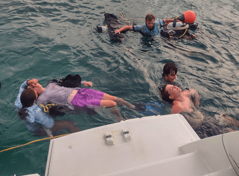 Middle school students practice rescue dive skills next to boat