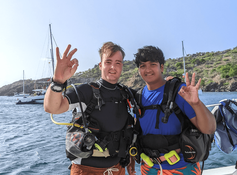Middle school student and dive instructor pose with dive gear on catamaran during summer dive trip