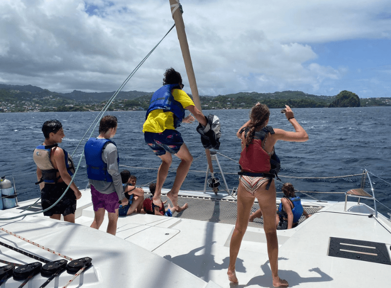 Teens on bow of catamaran during advanced scuba voyage through Caribbean Windward islands