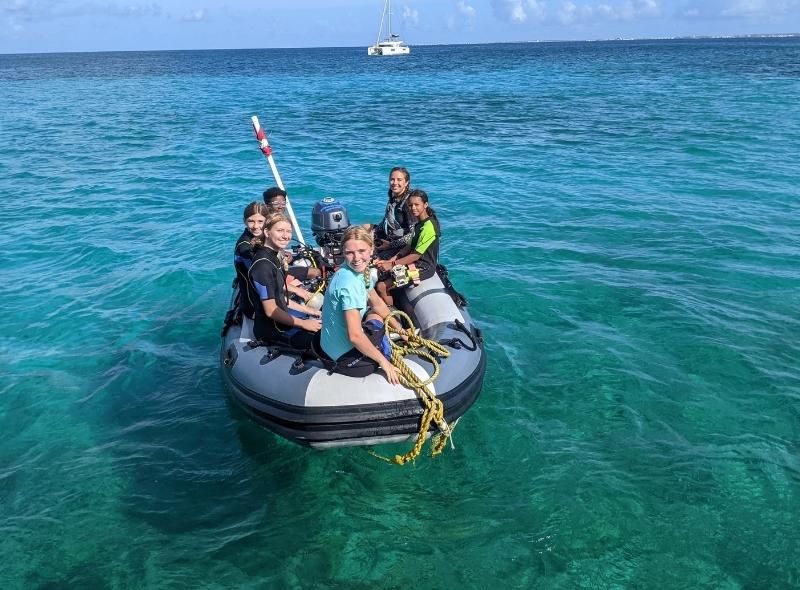 Teens on dinghy in scuba gear on marine biology camp