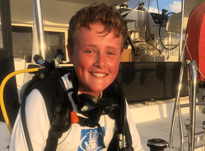 Middle school student in dive gear on catamaran at scuba program