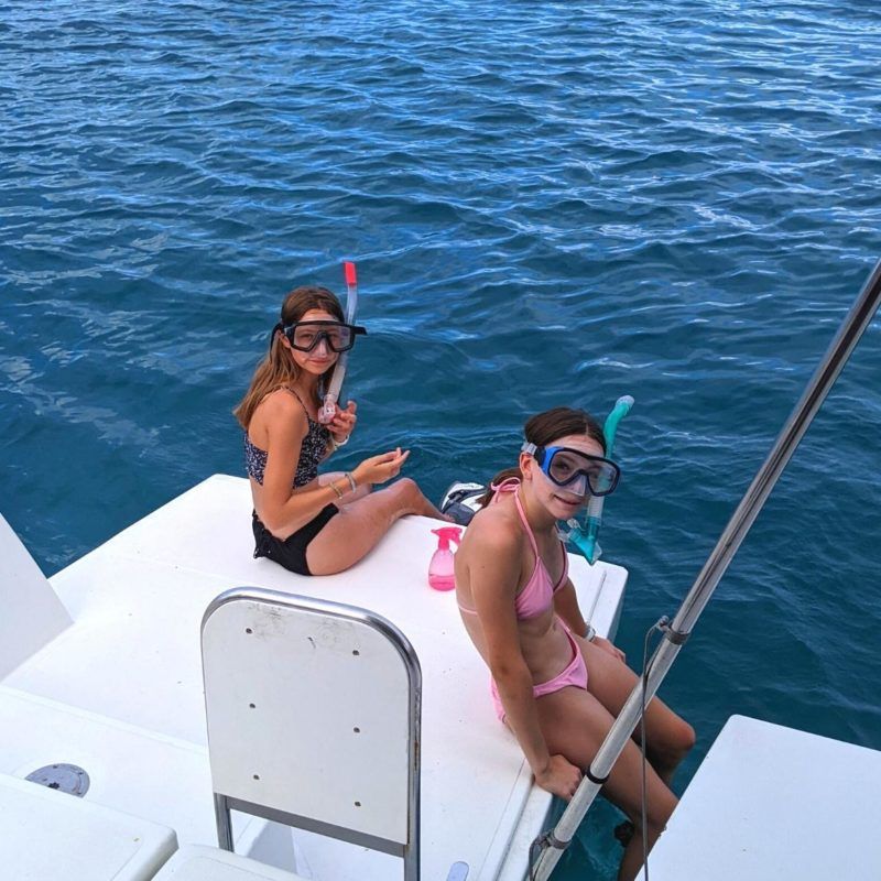 Middle school girls wear snorkels on sailboat in Caribbean at summer camp