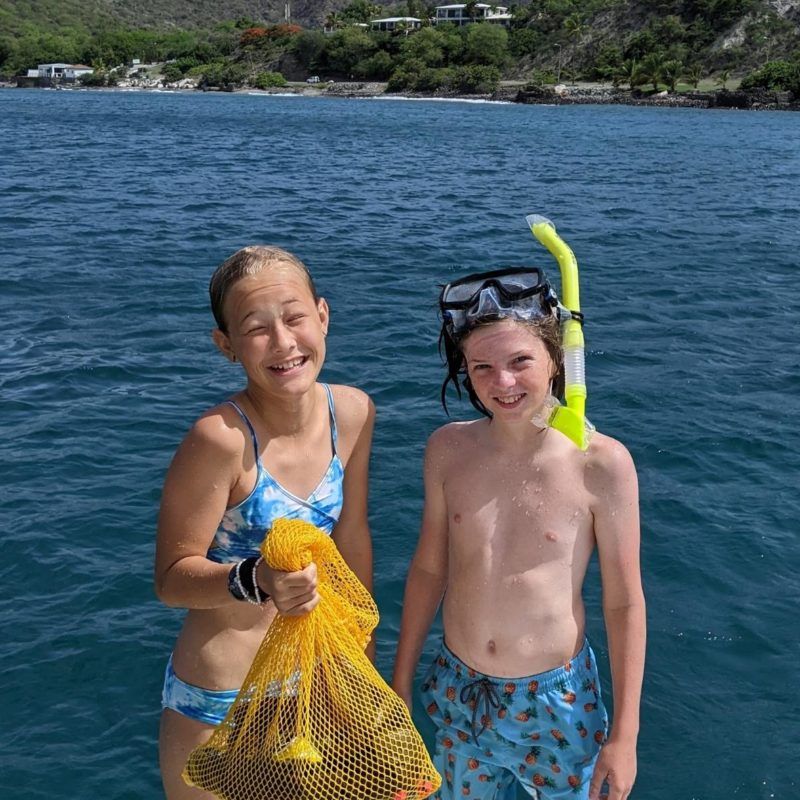 Two young teens wear snorkel gear on catamaran in Caribbean during camp