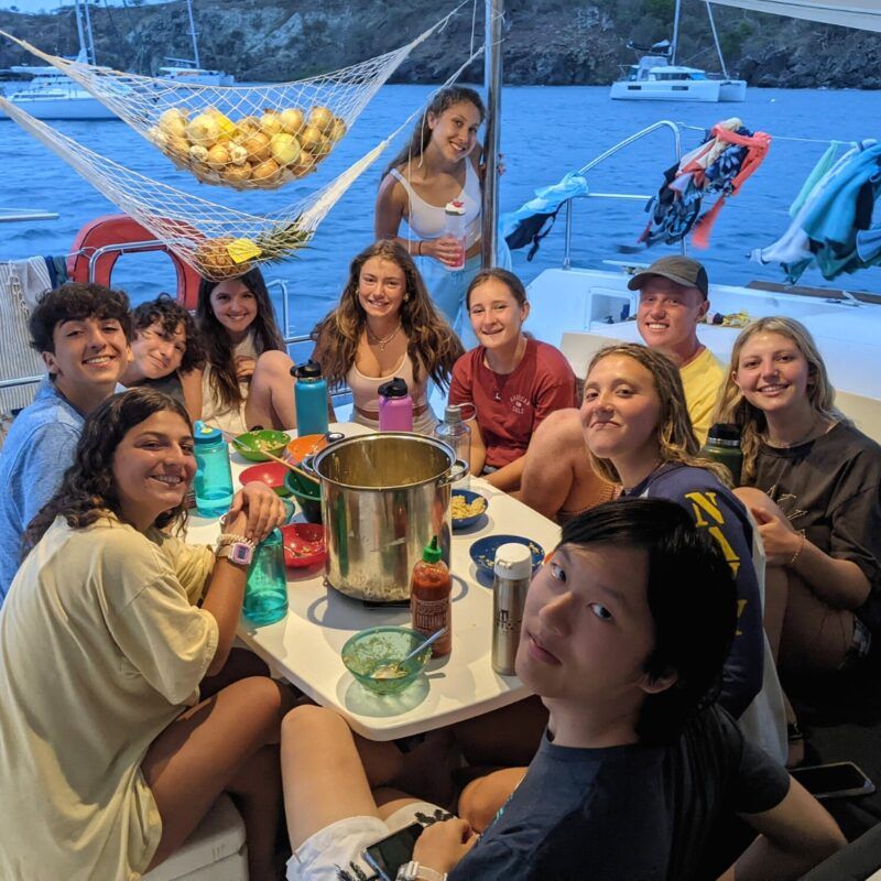 High school students share dinner on catamaran during sailing and scuba trip