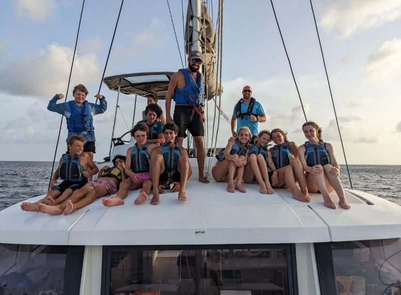 Group of teens and dive and sail instructors pose on catamaran for summer program