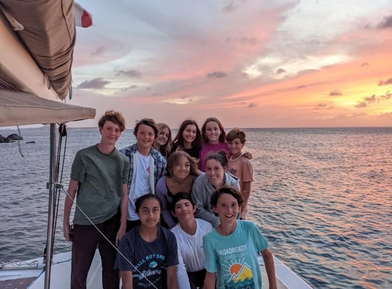 Group of middle school students pose on boat at sunset during scuba and sail program