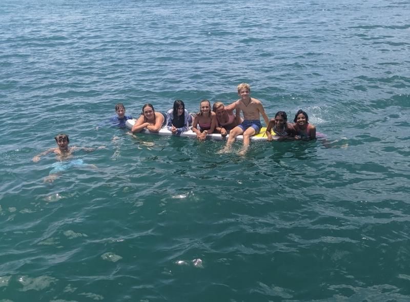 Group of middle school teenagers pose on Stand up paddleboard during dive trip