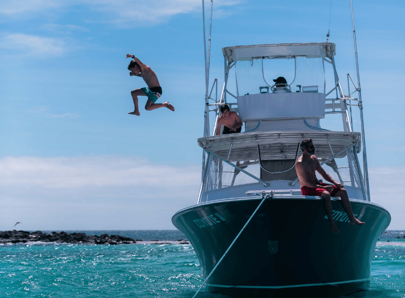 Teenager jumps from boat to water in Galapagos on wildlife biology summer camp for teens