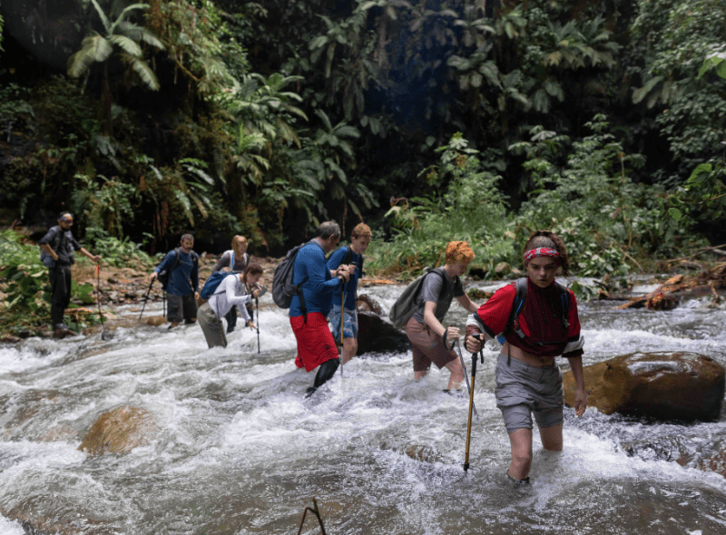 Teenagers wade river in Amazon studying wildlife biology on adventure camp