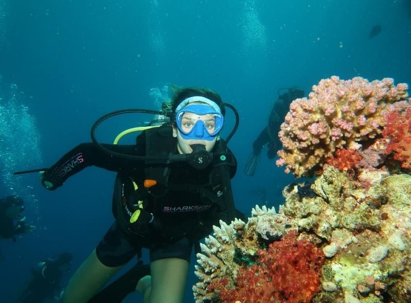 instructor poses near coral underwater during marine biology summer job