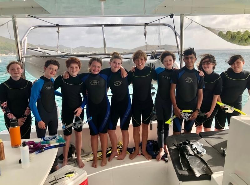 Group of middle school students in scuba gear pose on catamaran during liveaboard scuba and sailing camp in Caribbean for middle school students