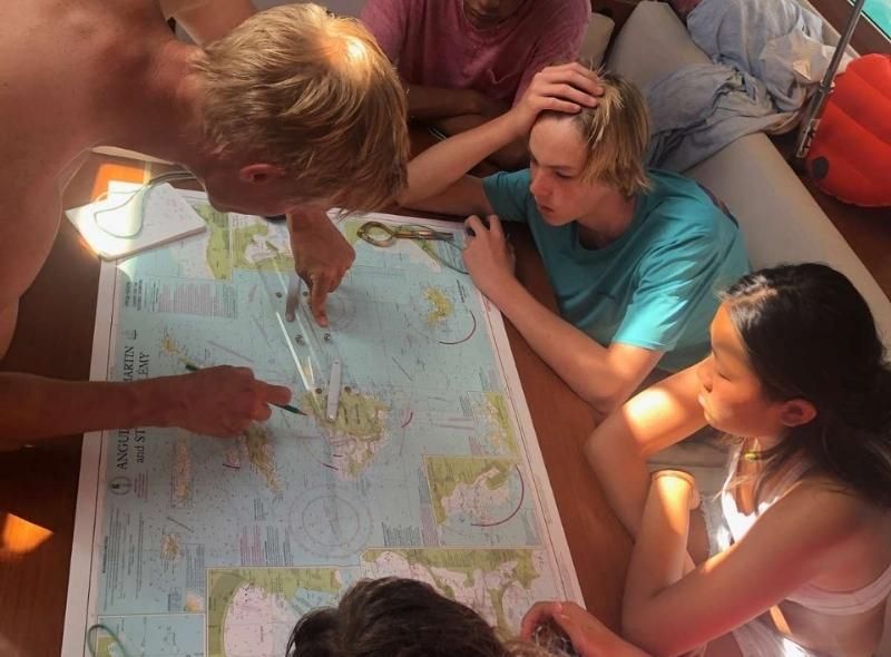 sailing instructor abroad assists teen students planning passage with map of Caribbean