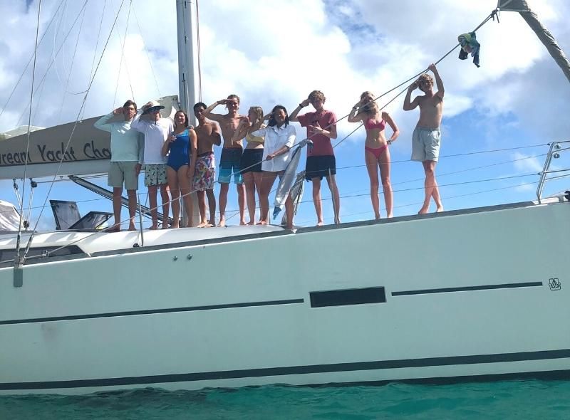 Group of teens on monohull at summer sailing camp in the Caribbean