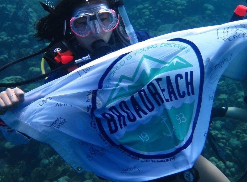 High school diver holds Broadreach flag underwater on teen scuba camp