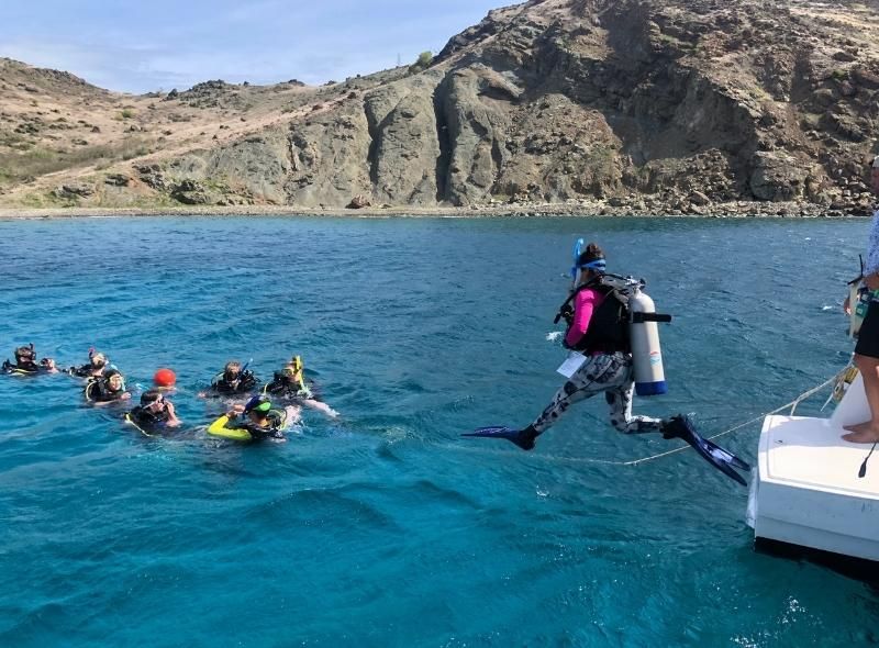 Group of high school students enter water in scuba gear on summer scuba program