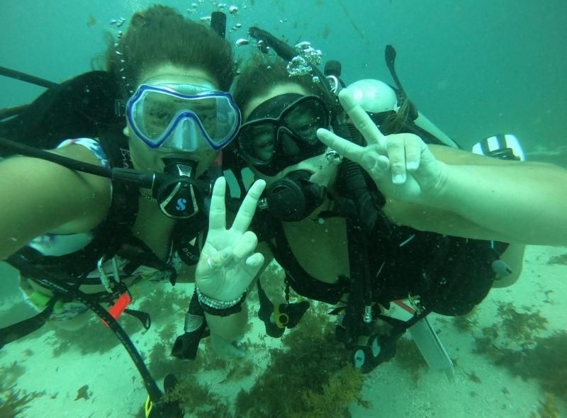 Teenage friends scuba dive in Caribbean on teen scuba camp