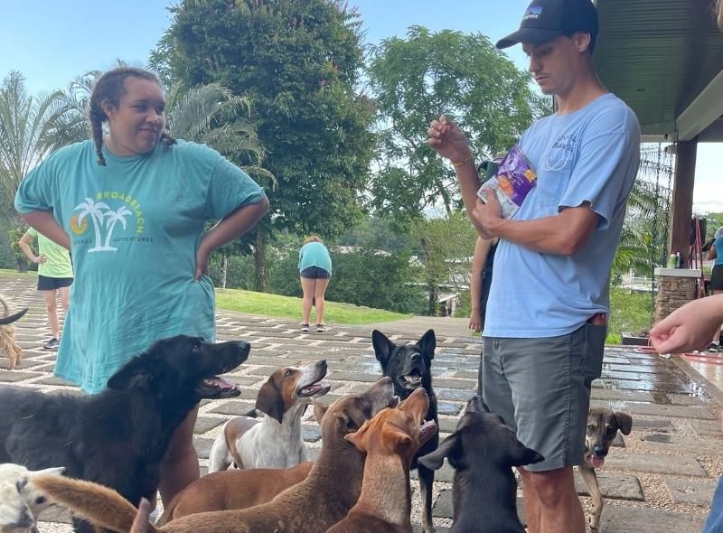 Male instructor and student stand with dogs at animal sanctuary in Costa Rica during veterinary summer job