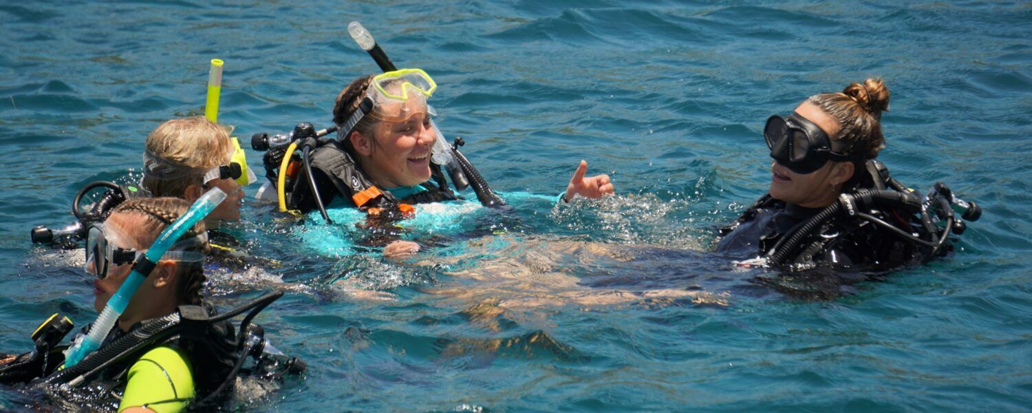 High school students in scuba gear earn PADI dive certification from instructor