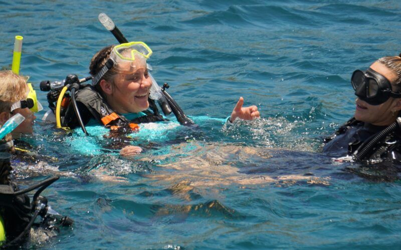 High school students in scuba gear earn PADI dive certification from instructor