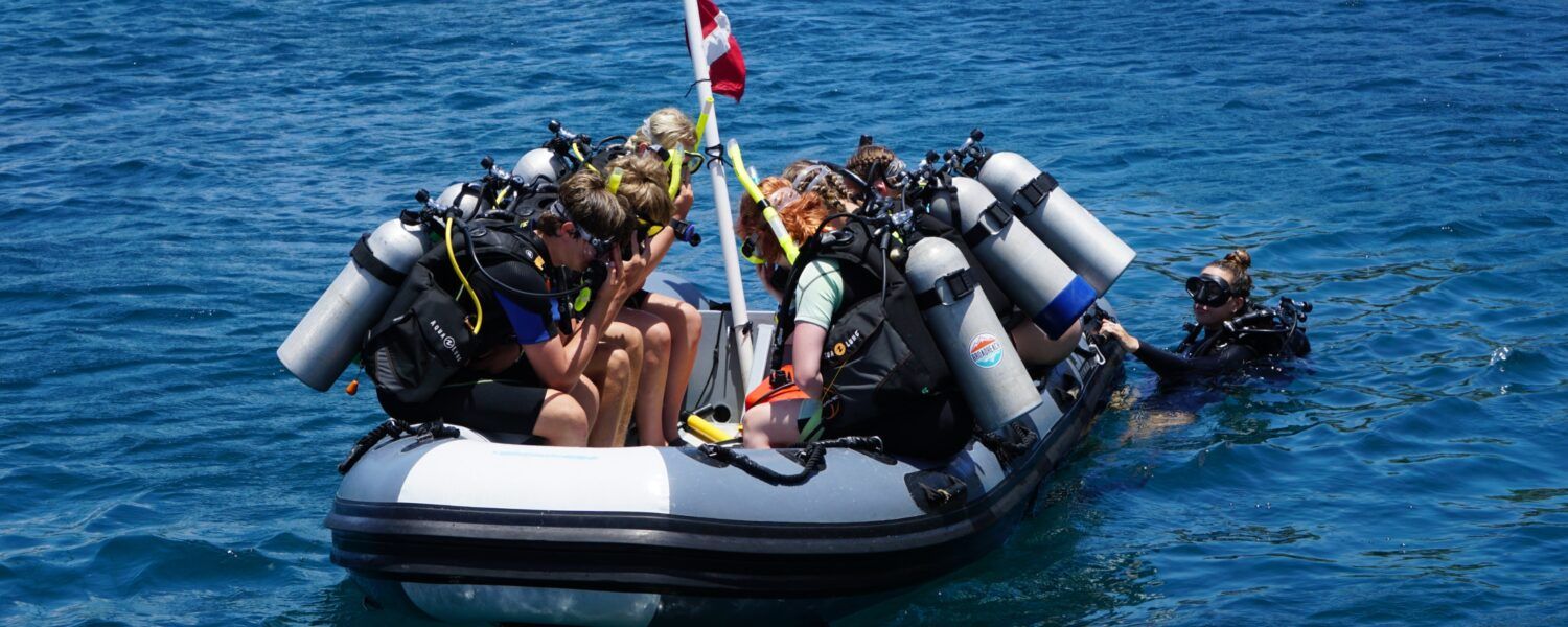 beginner divers diving off dinghy on introductory scuba program