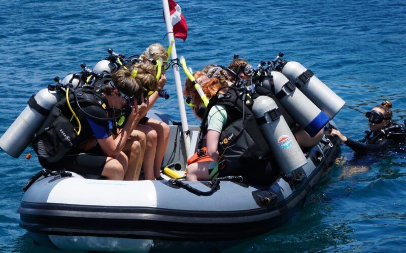beginner divers diving off dinghy on introductory scuba program