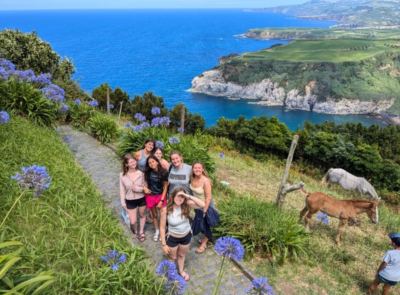 high school students pose on seaside cliff on whale and dolphin marine biology program on Azores
