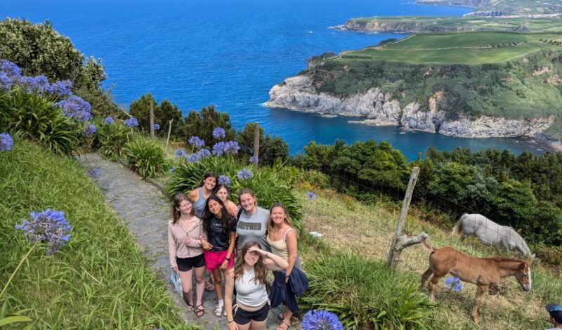 high school students stand on cliffs with ocean on marine biology whale trip in the Azores