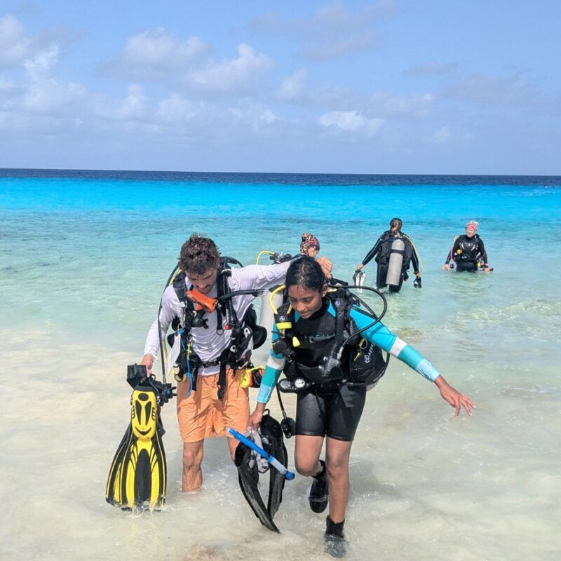 Middle school students in scuba gear in Bonaire step out of water on scuba program