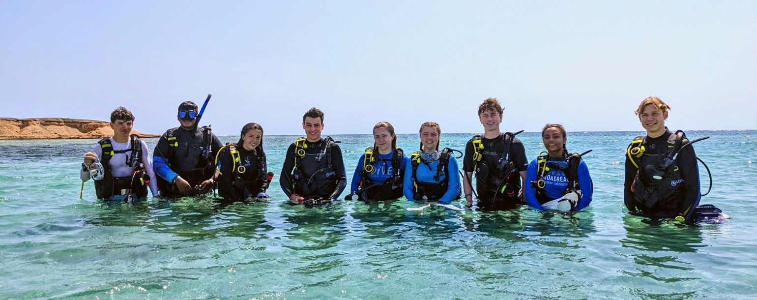 Teens in scuba gear in stand in water on summer scuba program