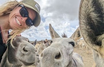 high school student poses with donkeys at Bonaire donkey sanctuary on scuba program