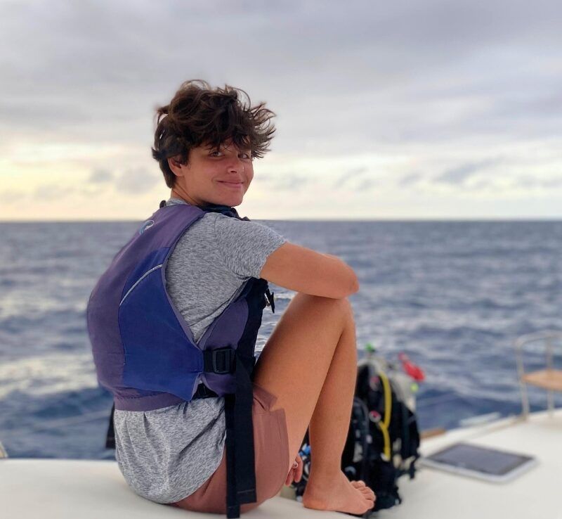 middle school boy sits on catamaran in Caribbean on dive and sail program