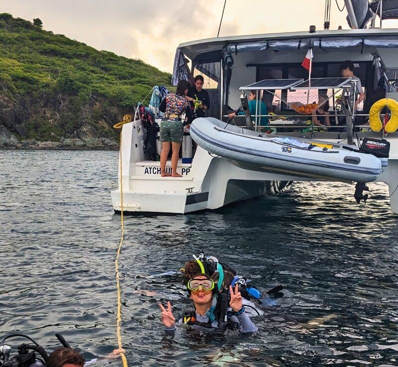 Students in dive gear in water near catamaran in the Caribbean