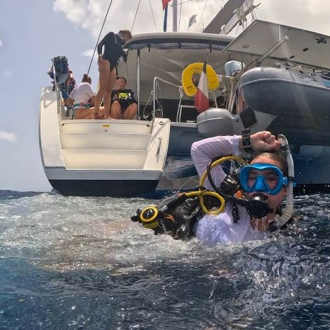 high school diver enters water with catamaran in background on Caribbean dive and sail weeklong program