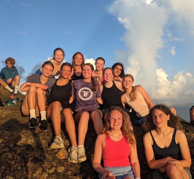 group of high school students pose at top of mountain in Caribbean 