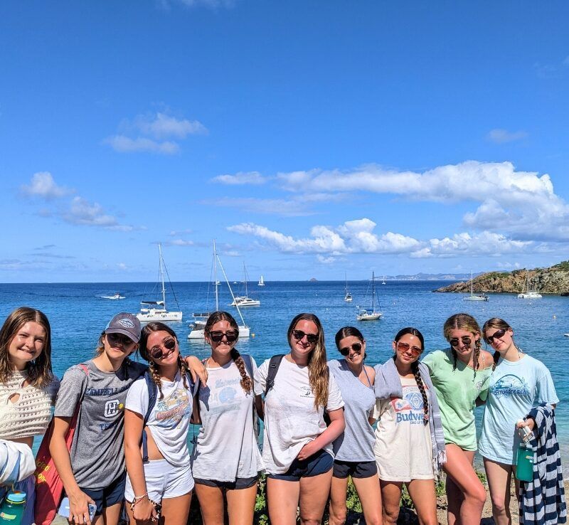 group of high school students on Caribbean island with bay and yachts in background.