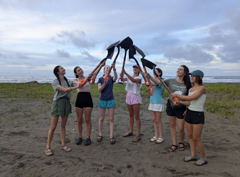 high school students raise shovels in air on Costa Rican beach on sea turtle conservation program