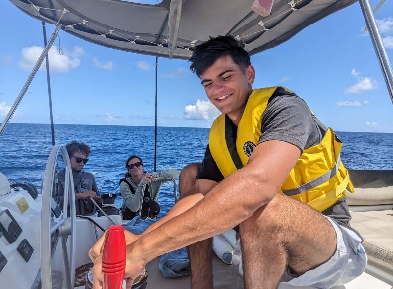 high school student assists with sailing catamaran on Caribbean sailing camp