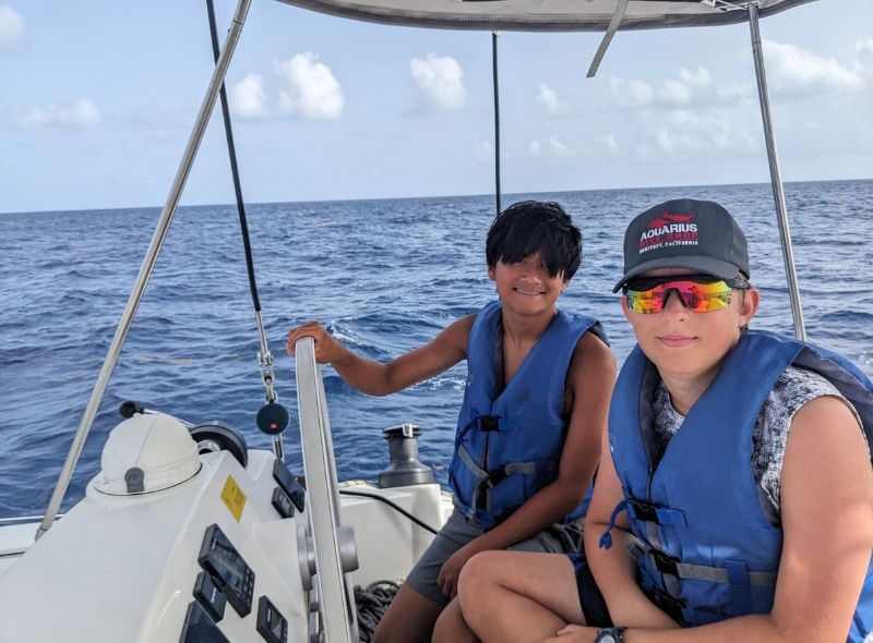 middle school students at the helm of a sailboat on summer sailing program